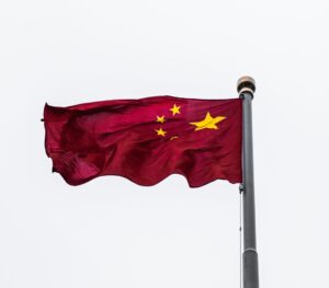 The flag of the People's Republic on China flying at the top of a pole.