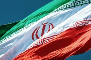 A close-up shot of the Iranian flag flying against a blue sky