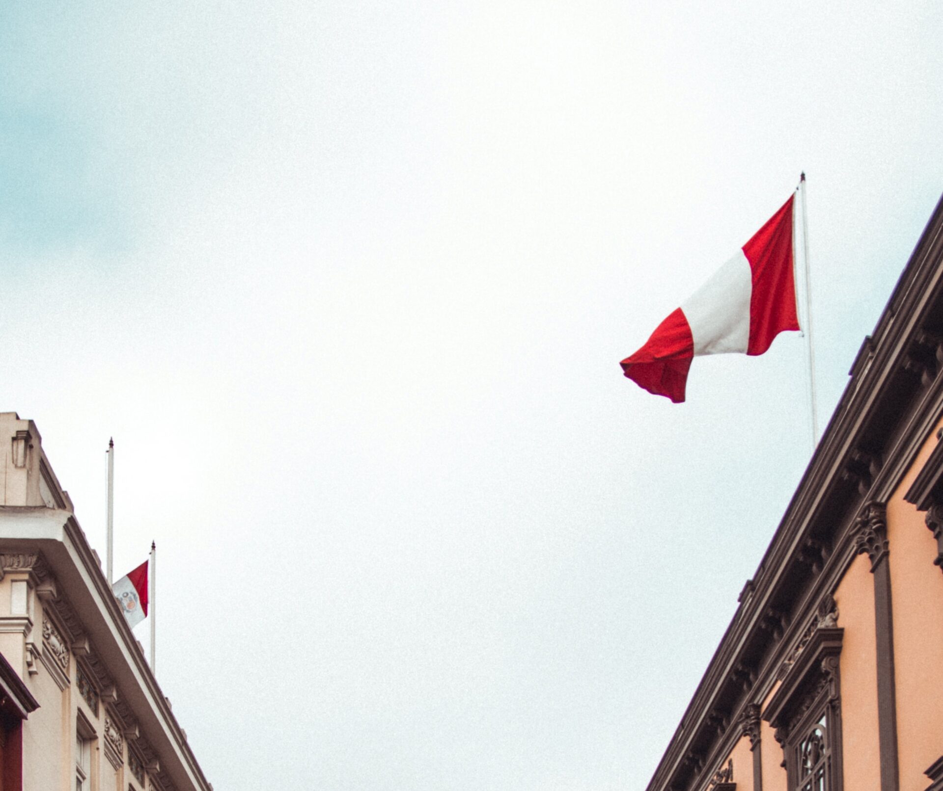 the peruvian flag flying in the wind on top of a building