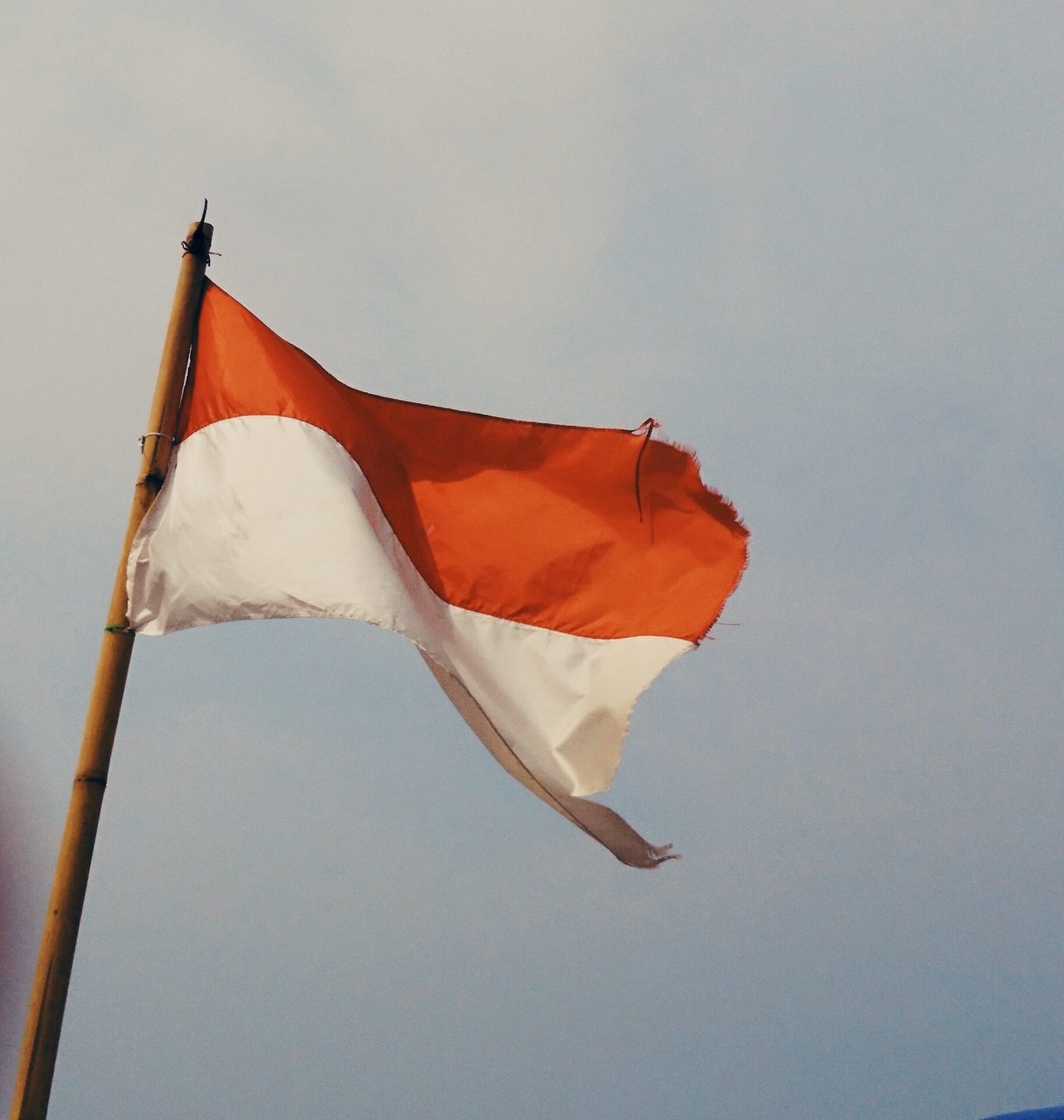 the flag of Indonesia flying against a blue sky