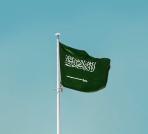 The flag of Saudi Arabia flying against a blue sky.