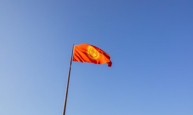 Flag of Kyrgyzstan on a pole against a blue sky