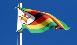 the flag of zimbabwe flying against a blue sky