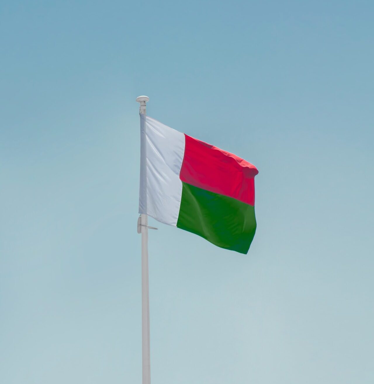 The flag of Madagascar flying against a blue sky