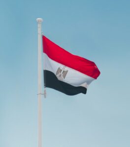 The Egyptian flag is flying against a light blue sky.