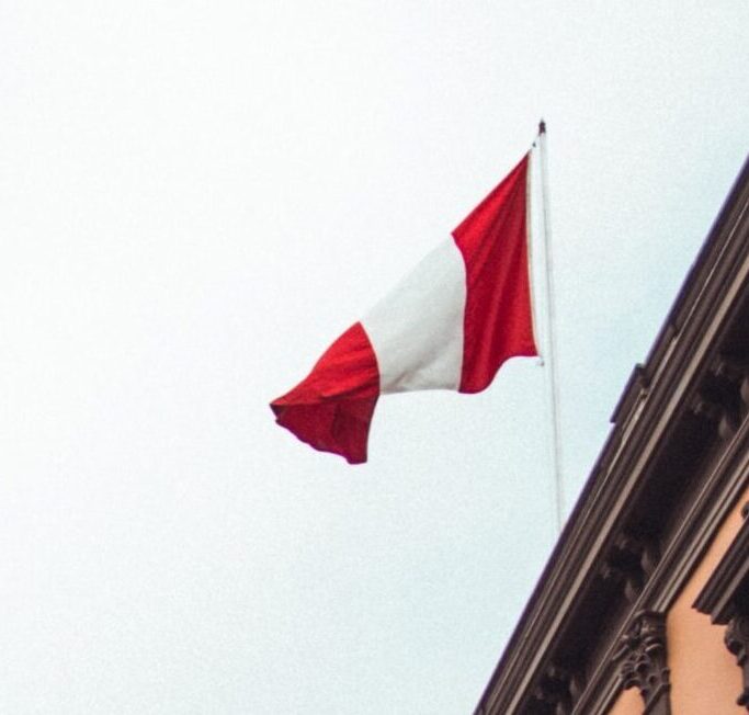 the peruvian flag flying in the wind on top of a building