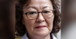 A close up photo of Mongolian woman human rights defender Sukhgerel Dugersuren. She is wearing her wavy brown hair in a short bob and has glasses.