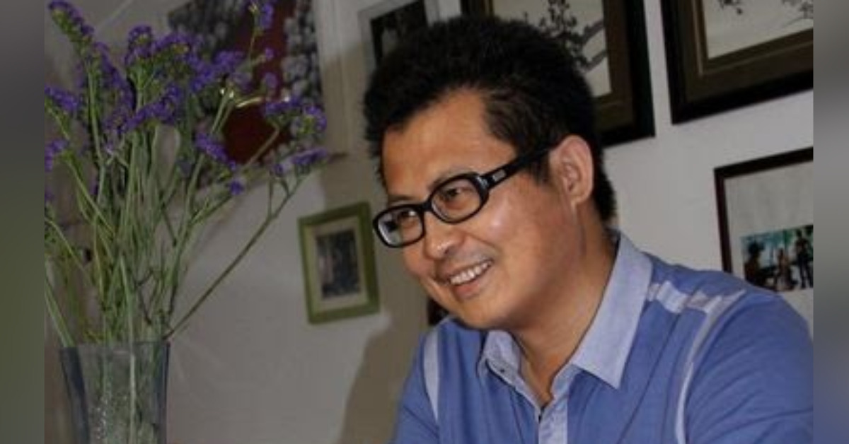 Guo Feixiong before he was detained. He is wearing black frame glasses and a blue polo shirt. He is smiling and looking to the left.