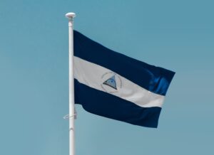 The flag of Nicaragua flying in the wind against a blue sky background.
