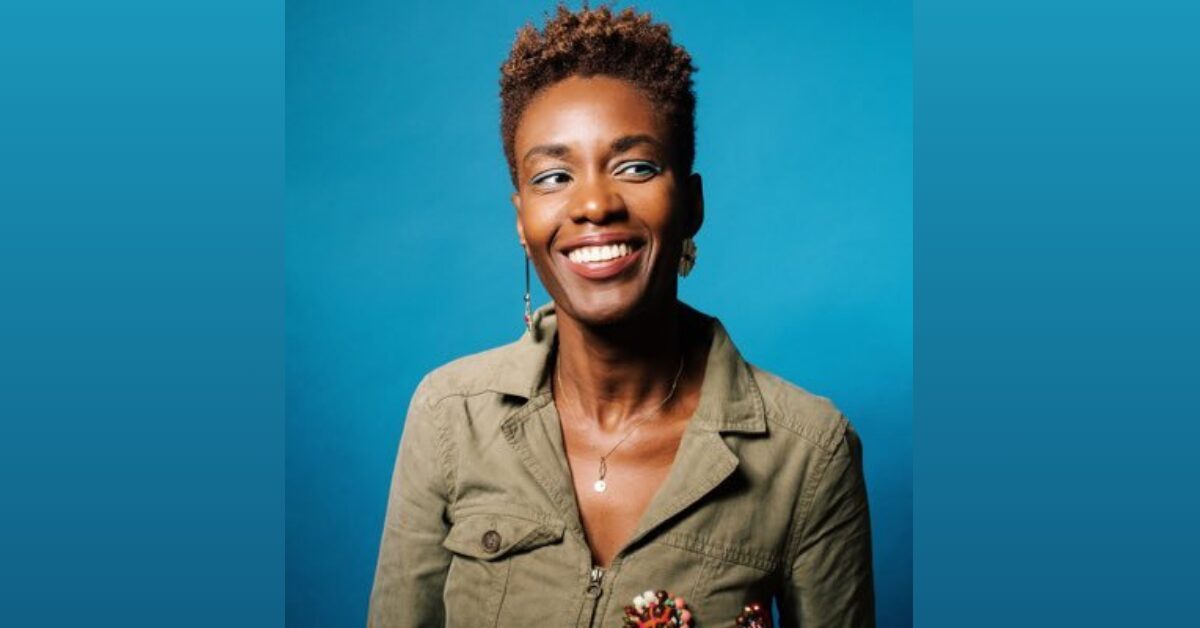 French author and human rights defender Rokhaya Diallo, a black woman, photographed in front of a teal background. She is smiling and looking to the right