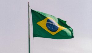The Brazilian flag on a pole blowing in the wind. The flag is green with a yellow diamond at its centre, inclosing a blue disc with a starry sky.
