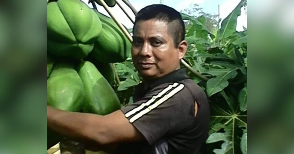 El defensor de los derechos humanos mexicano Versain Velasco García está de pie entre árboles y plantas. Lleva una camiseta negra con dos rayas blancas en la manga.
