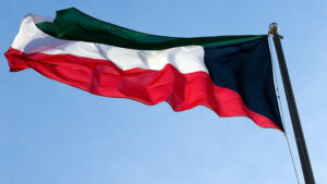 The flag of Kuwait blowing in the wind under the blue sky.