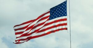 The flag of the United States of America flying against a cloudy sky.