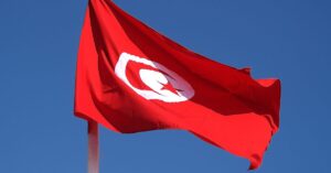 The flag of Tunisia flying in the wind under a blue sky