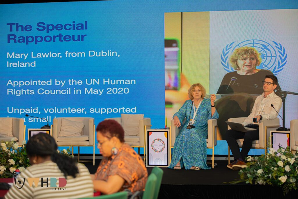 UN Special Rapporteur on human rights defenders Mary Lawlor and her senior advisor Ed O'Donovan are sitting on a stage during the WHRD Convention in Ghana, presenting the work of the mandate to the audience. 