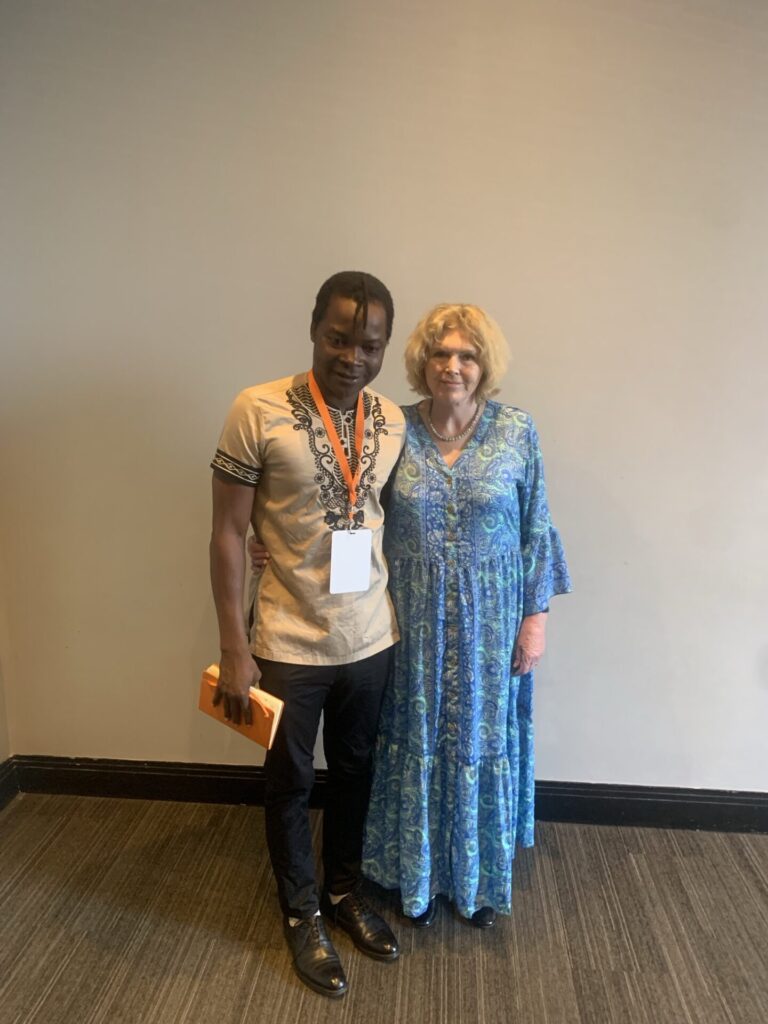 UN Special Rapporteur on human rights defenders Mary Lawlor and human rights defender Robson Chere from Zimbabwe stand side by side, smiling warmly at the camera. 