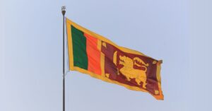 The flag of Sri Lanka flying in the wind against a grey sky background.