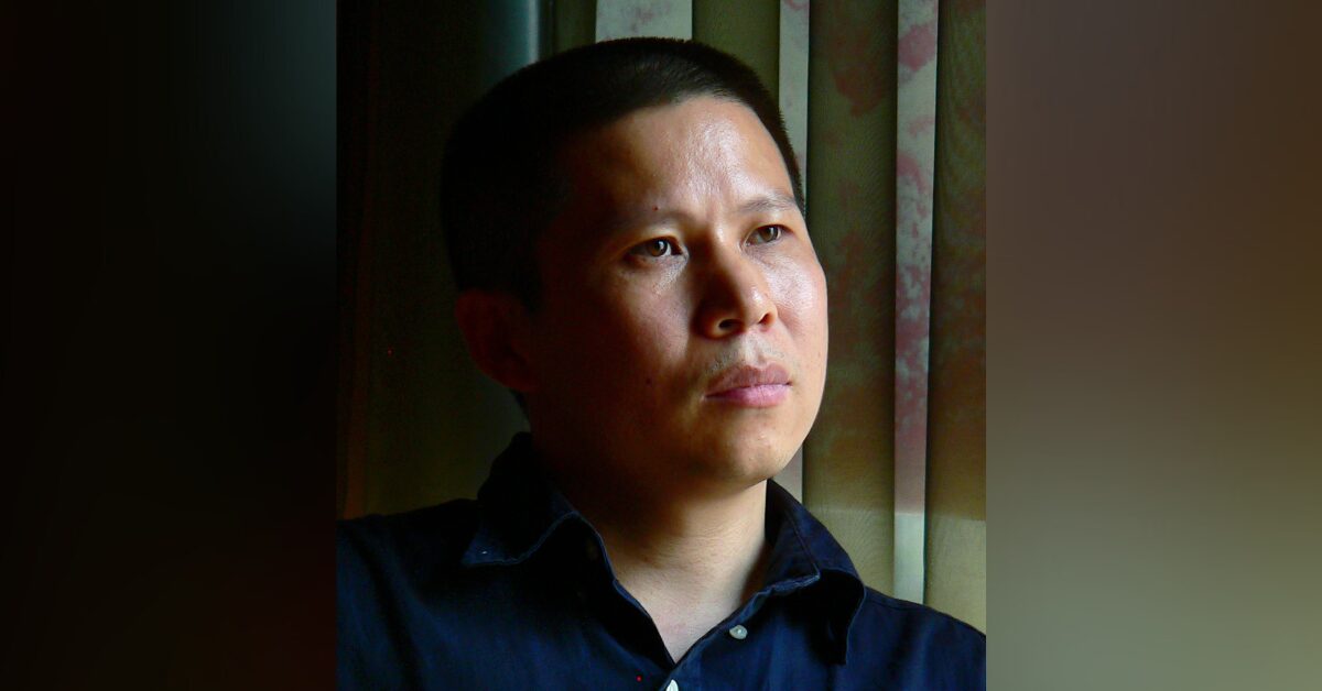 Portrait of Chinese human rights defenders Xu Zhiyong in front of a dark background. His expression is calm and focused, with a gaze directed slightly away from the camera.