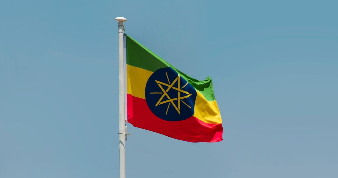 The flag of Ethiopia flying in the wind against a blue sky background.
