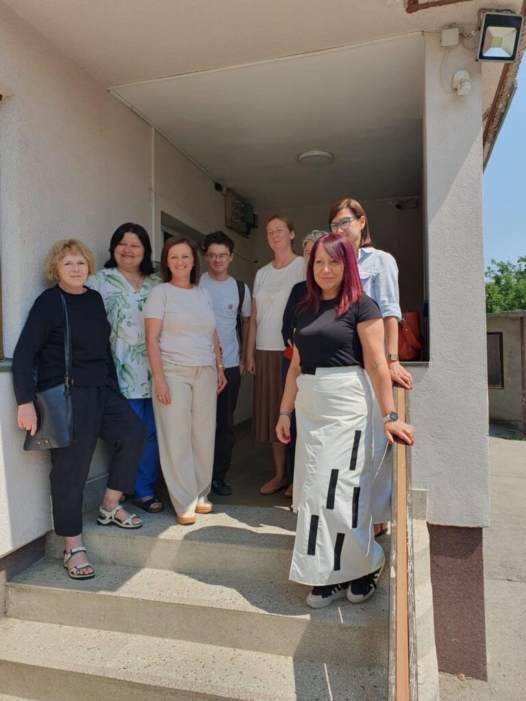 Mary Lawlor, UN Special Rapporteur on human rights defenders, stands with a group of women human rights defenders from the LARA Foundation during her country visit to Bosnia and Herzegovina. They are gathered outside the entrance of a building, smiling together on a sunny day.