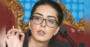Pakistani human rights lawyer Imaan Zainab Mazari speaks at an event, wearing glasses and a dark jacket, seated on an ornate chair with a microphone in front of her.