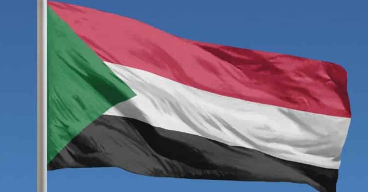 The flag of Sudan is flying against a blue sky background.