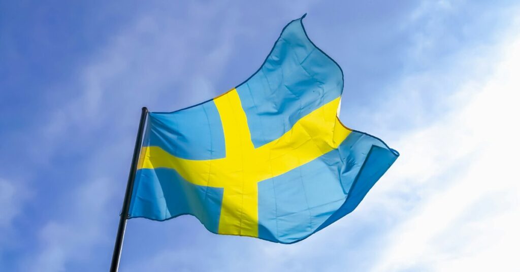 The flag of Sweden flying in the wind under a bright blue sky