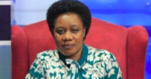 Uganda lawyer and human rights defender Ms. Sarah Bireete is looking straight at the camera with a serious expression on her face. She is wearing a white and green floral top and is sitting in a red chair.