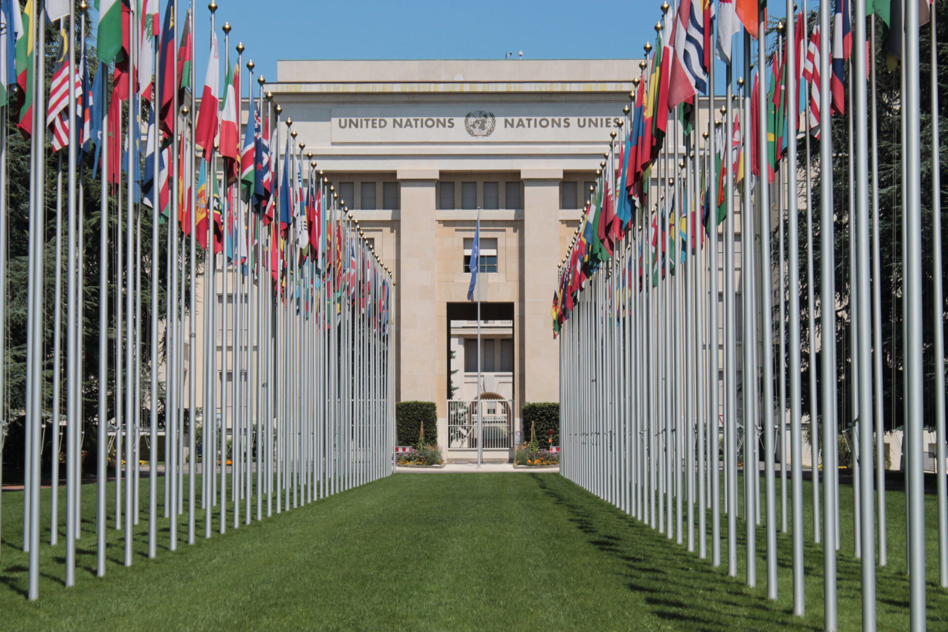 Flags of United Nations Member States lining the grassy lawn in front of the UN Headquarters in Geneva, Switzerland