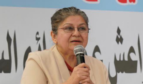 The woman human rights defender and feminist Yanar Mohammed, standing in front of a row of microphones holding a microphone herself